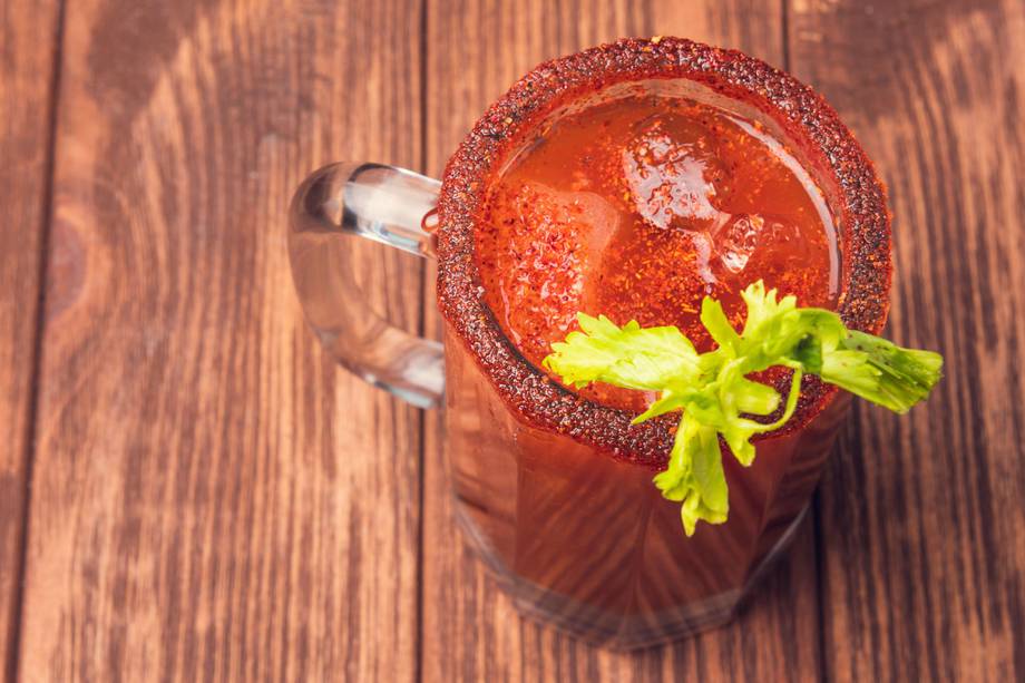 Michelada beer with tomato juice. Clamato with beer on wooden table. Mexican drink. Concept of mexican frink