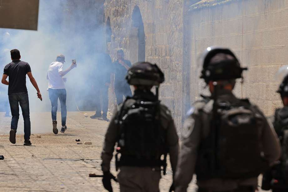 Palestinos corren del gas lacrimógeno lanzado por la policía israelí.