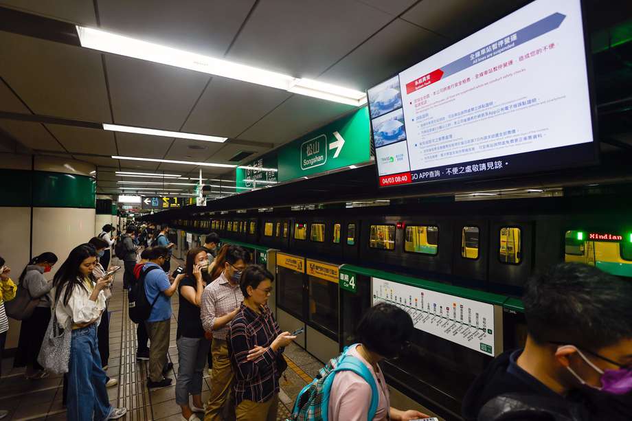 Los pasajeros esperan debajo de una pantalla que transmite un anuncio de suspensión del tren subterráneo después de un terremoto de magnitud 7,4 cerca de Hualien, en una estación de metro en Taipei, Taiwán, 03 de abril de 2024.
