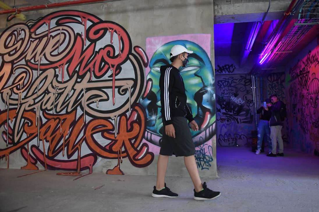 Un hombre caminando junto a un grafiti