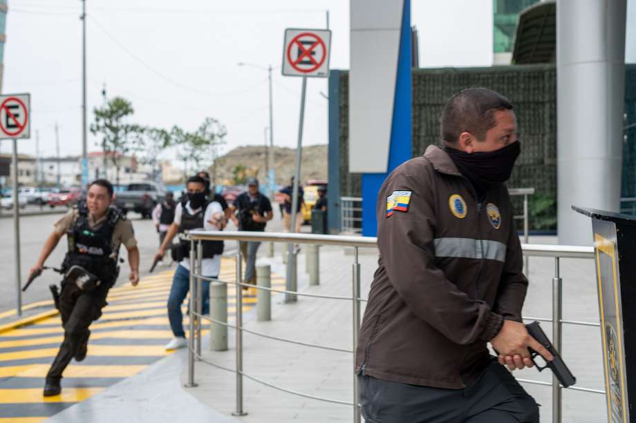  Policías persiguen  a un presunto delincuente a pocas cuadras de la sede del canal de televisión TC, donde encapuchados armados ingresaron y sometieron a su personal durante una transmisión en vivo, en Guayaquil (Ecuador).