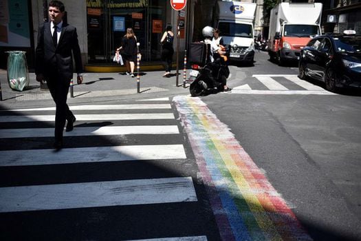 Peatones caminan por un paso de cebra con un arco iris pintado en una calle en el barrio de Marais en París. / Julien De Rosa - EFE