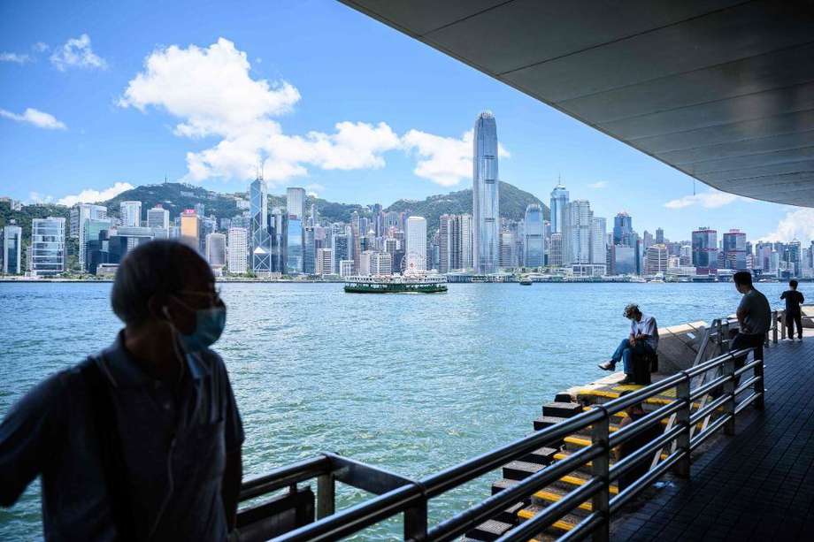 Las personas usan máscaras faciales mientras visitan un paseo marítimo en el lado de Kowloon del puerto de Victoria, que mira hacia el horizonte de la isla de Hong Kong.