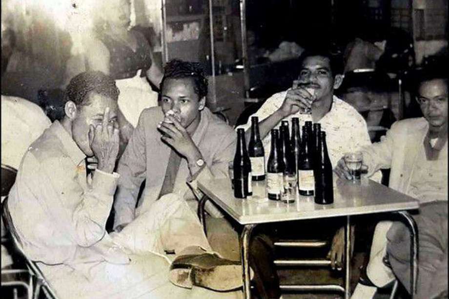 Miguel Ángel Araque Bolaños por la época en que laboró con la casa disquera Fuentes en Medellín, hace pistola, mientras comparte unas cervezas con algunos de sus compañeros de trabajo.