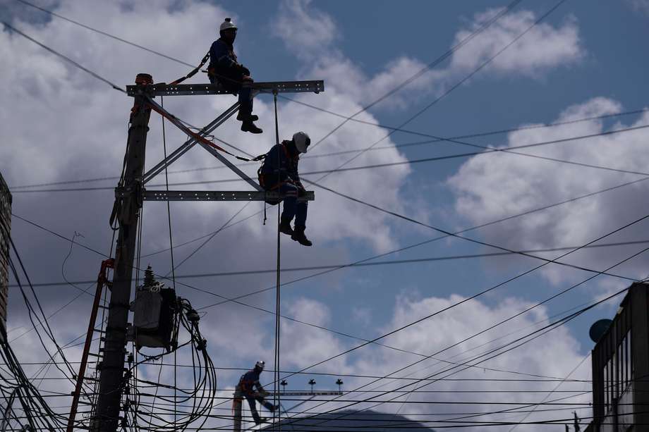 Hombres trabajando en un poste de energía eléctrica.
