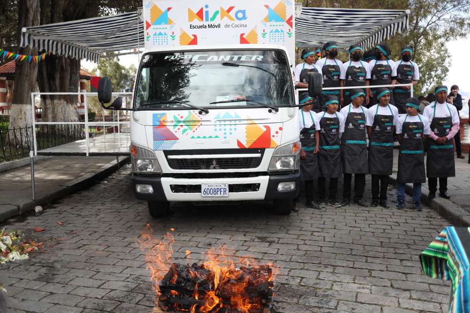 Estudiantes de gastronomía posan delante la escuela móvil de cocina "Miska".
