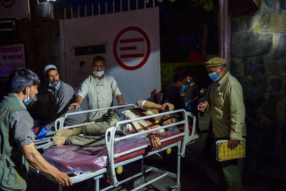 Personal médico y hospitalario lleva a un herido en camilla para recibir tratamiento tras dos potentes explosiones fuera del aeropuerto de Kabul el 26 de agosto de 2021.