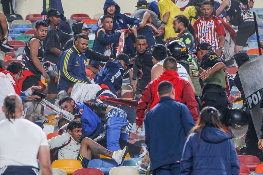 Hinchas de Junior se enfrentan con integrantes de la Policía de Perú en un partido de la fase de grupos de la Copa Libertadores entre Universitario y Junior en el estadio Monumental.