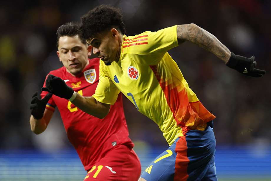 El delantero colombiano #07 Luis Díaz (R) corre con el balón junto al mediocampista rumano #21 Olimpiu Morutan durante el partido de fútbol amistoso internacional entre Rumania y Colombia en el estadio Metropolitano de Madrid el 26 de marzo de 2024.