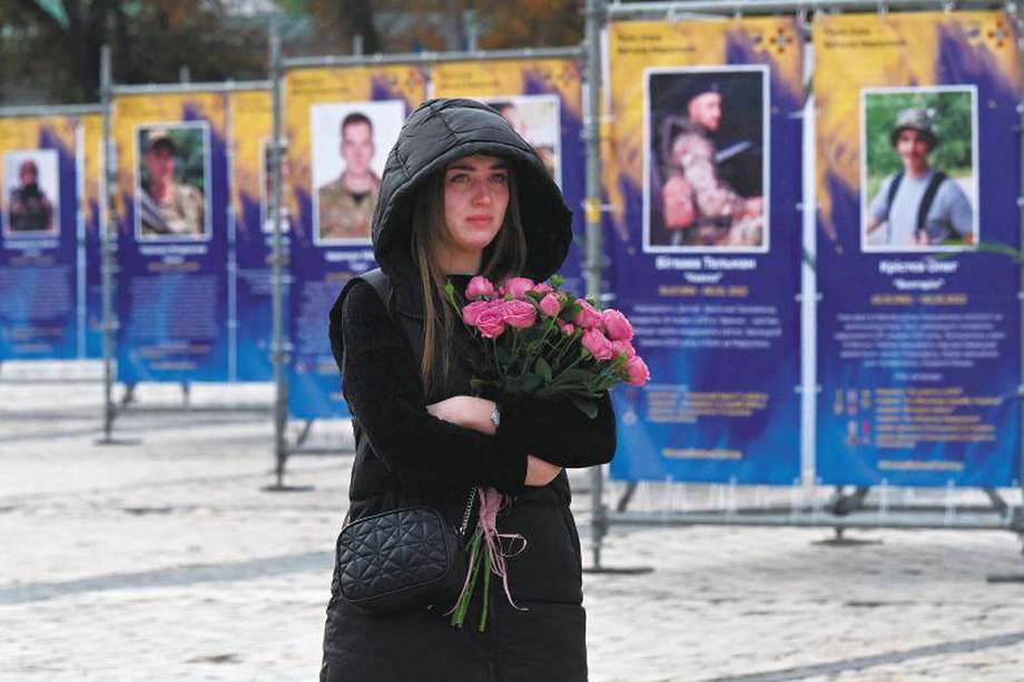 Una joven lloraba mientras caminaba entre retratos de militares muertos durante la inauguración de la exposición "Regimiento Azov - Ángeles de Mariupol", en el centro de Kiev, en conmemoración al Día de los Defensores de Ucrania, el 14 de octubre de 2022. 