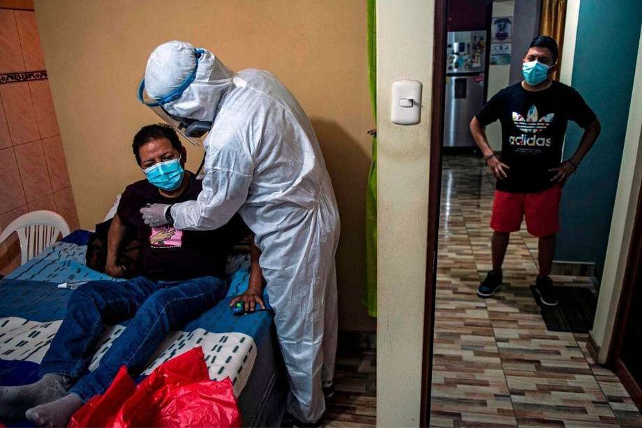 Un paciente de Covid-19 es revisado por un médico durante una visita a su casa en las afueras del este de Lima, Perú.
