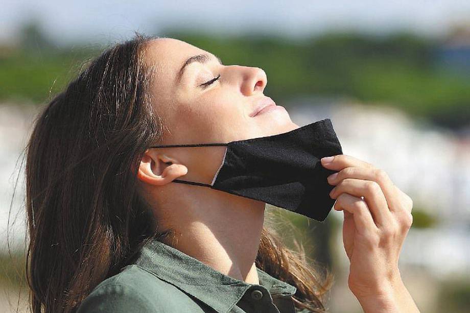 Woman taking off mask breathing fresh air in a town
