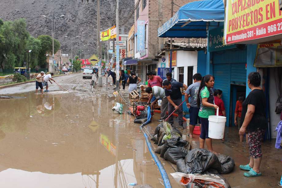 Residentes intentan sacar el agua de sus casas y locales inundados por el ciclón Yaku, en el distrito de Chaclacayo en Lima (Perú).