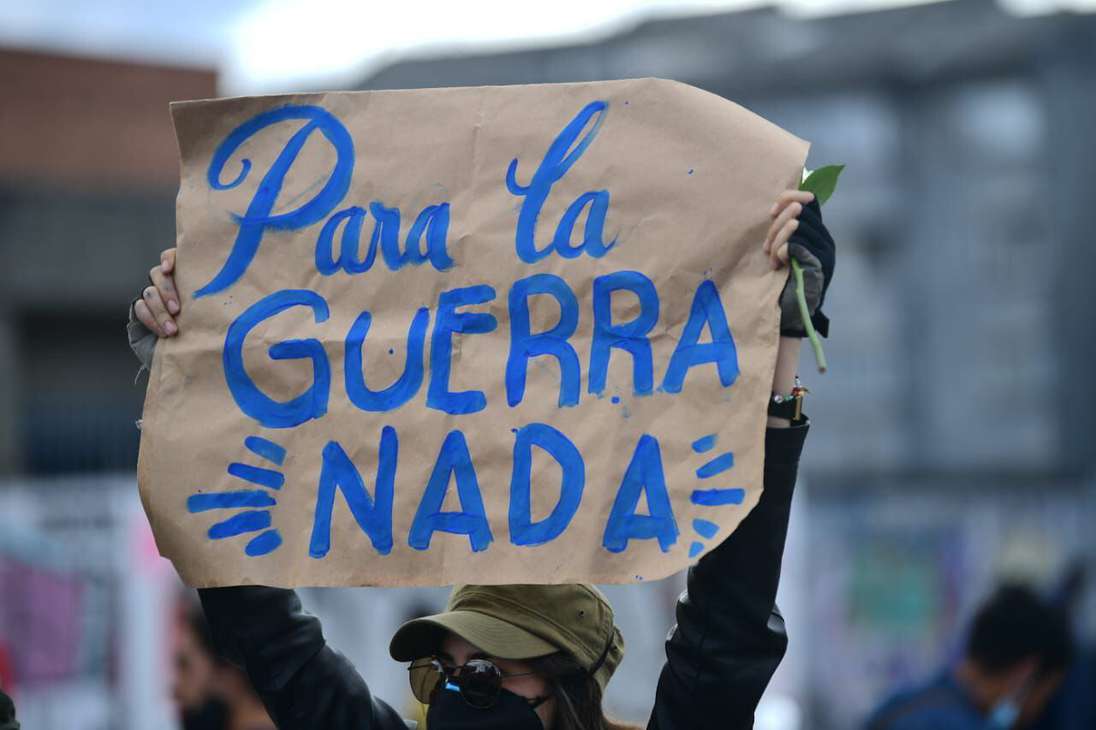 Una mujer sostiene un letrero que dice: para la guerra nada