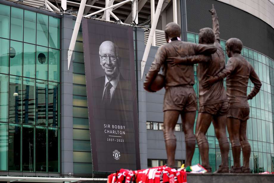 Una imagen de Bobby Charlton colgada en el estadio de Old Trafford frente a la estatua de la "santísima trinidad" del equipo. Charlton es uno de ellos. Los otros son George Best y Dennis Law.