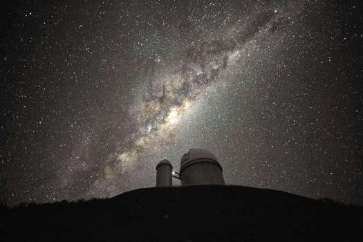 Foto del Observatorio Austral Europeo (ESO). Sobre la cúpula del telescopio, se encuentra el prominente y amarillento bulbo central de la Vía Láctea. Dos equipos científicos han obtenido el mapa tridimensional más completo hasta la fecha del corazón de nuestra galaxia. 