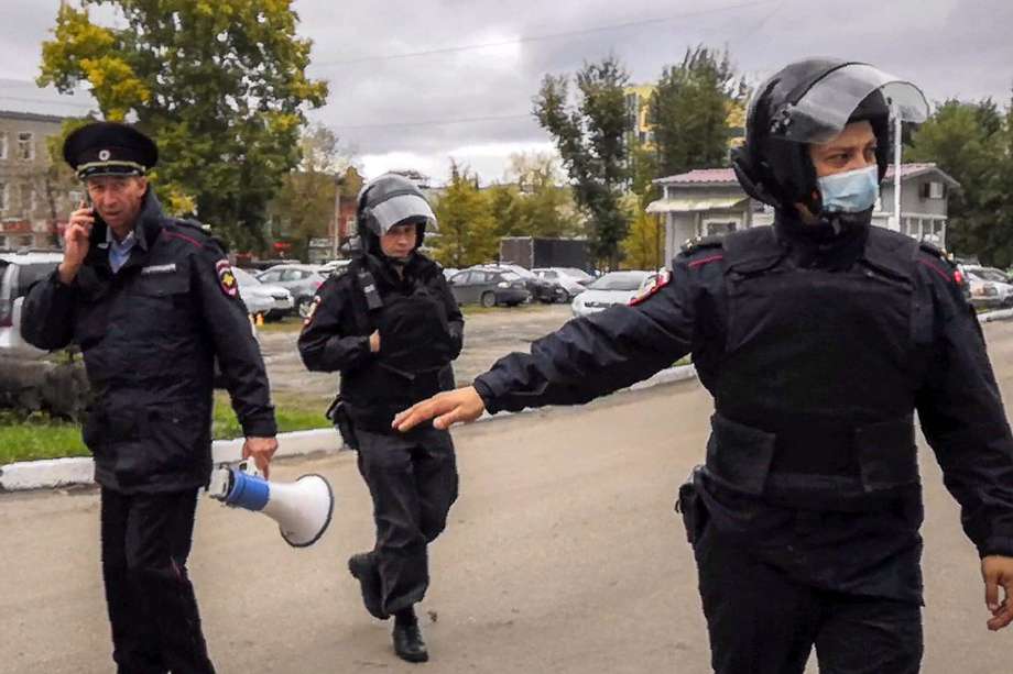 Los oficiales de policía vigilan mientras los estudiantes evacuan un edificio del campus universitario de Perm