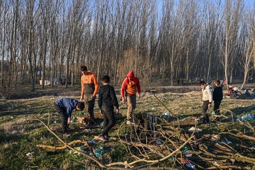 Migrantes sirios en la frontera entre Turquía y Grecia recogen madera para encender una fogata.  / AFP