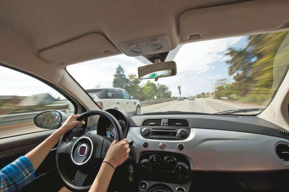 A woman driving a small car down a california highway.