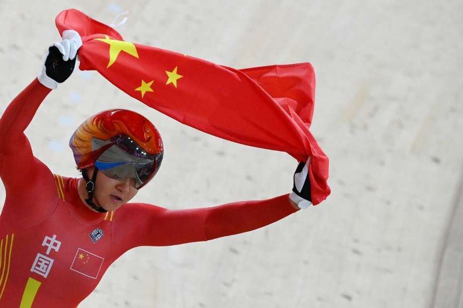 Zhong Tianshi, miembro del equipo chino de ciclismo de pista, celebra con la bandera china.