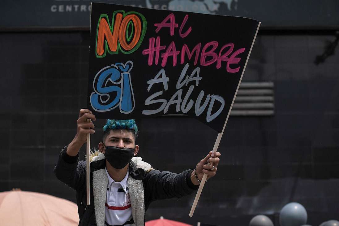 Un joven con una pancarta que dice: no al hambre si a la salud.