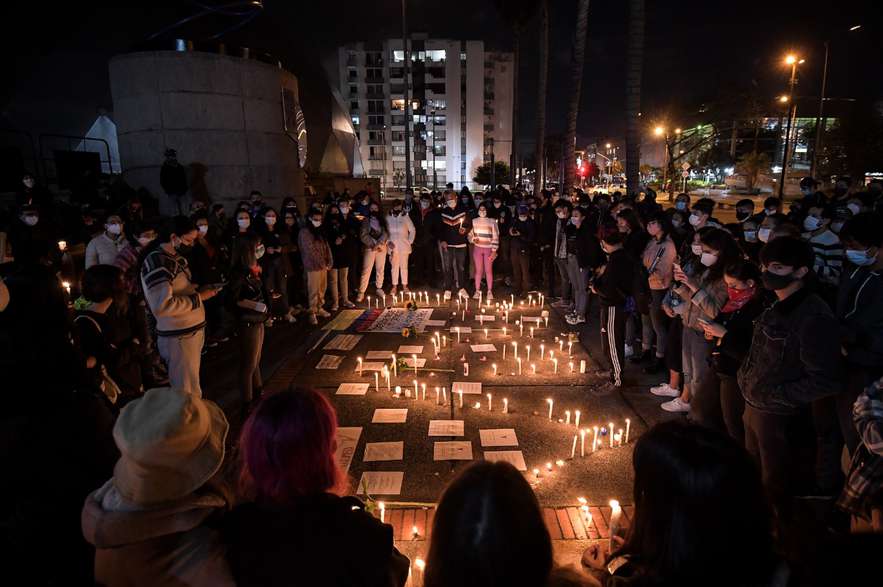 Varias personas alrededor de velas y mensajes escritos en papeles en el suelo