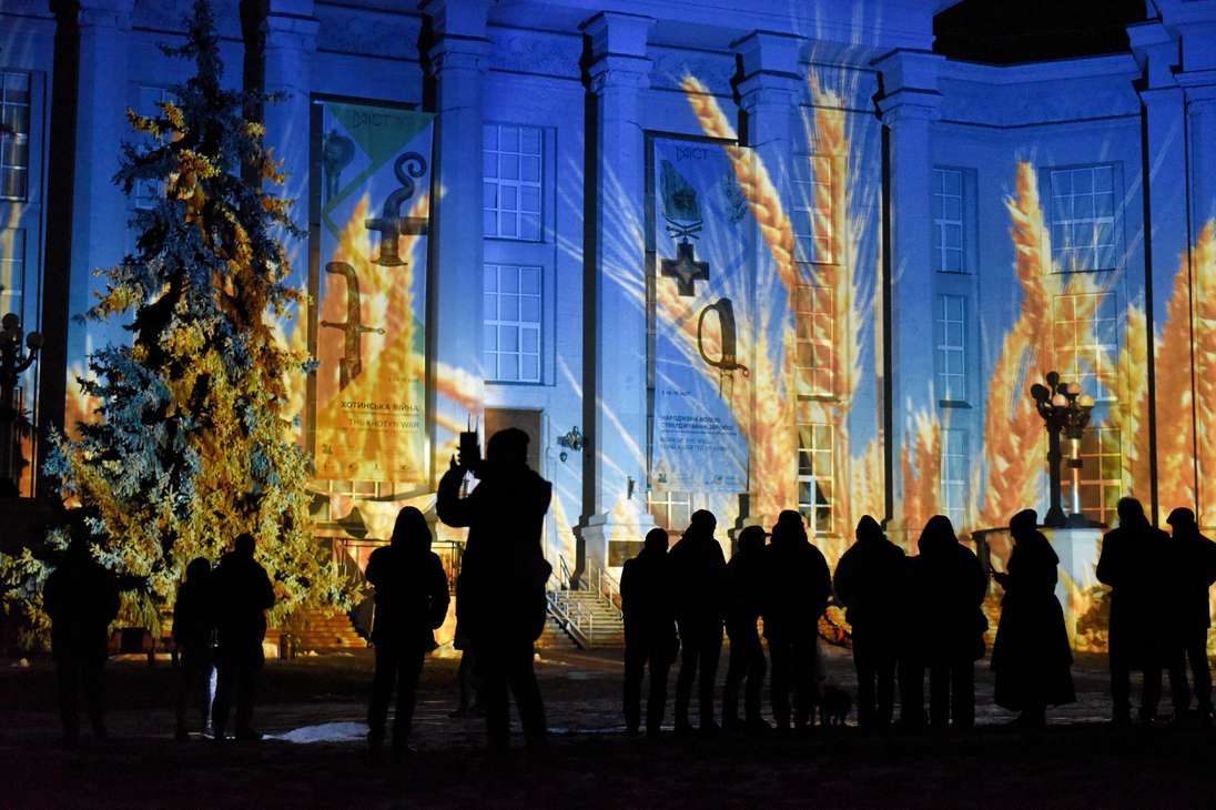 Kyiv (Ukraine), 23/12/2022.- People watch the National Historical Museum illuminated by Swiss light artist Gerry Hofstetter in Kyiv, Ukraine, 23 December 2022. Hofstetter is performing a Christmas art tour in Kyiv on 23 to 25 December during which he will illuminate residential buildings, museums, universities, and churches buildings with Christmas motifs, the Ministry of Culture and Information Policy of Ukraine said. (Ucrania) EFE/EPA/OLEG PETRASYUK