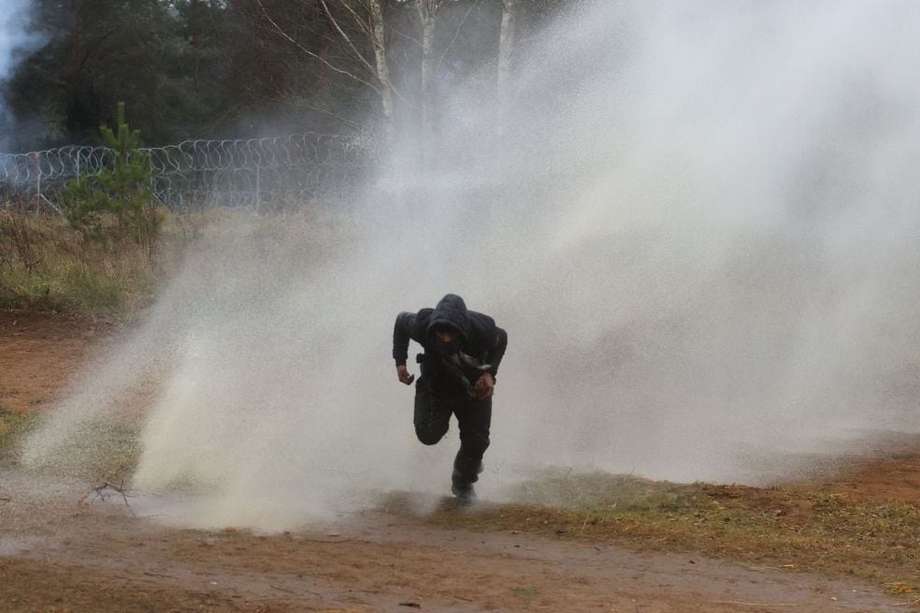 Un hombre huye de los cañones de agua disparados por las fuerzas polacas en la frontera con Bielorrusia.