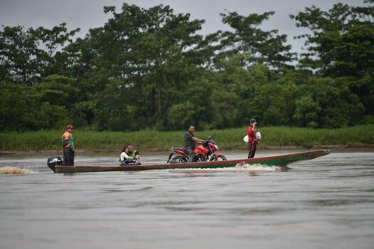 Un migrante, que se dirigía hacia Colombia desde el lado venezolano, pasa la frontera en canoa montado en su motocicleta.