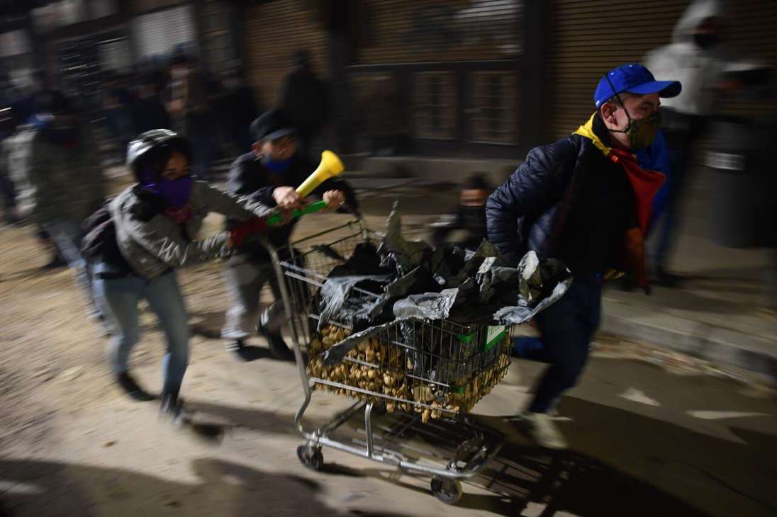 Un hombre empuja un carro de supermercado junto a dos mujeres encapuchadas.