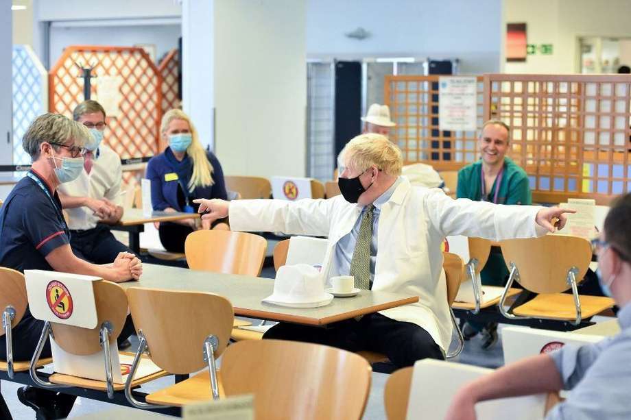 El primer ministro británico, Boris Johnson, usa una mascarilla facial mientras se sienta con los trabajadores de un hospital en Reading, al oeste de Londres.