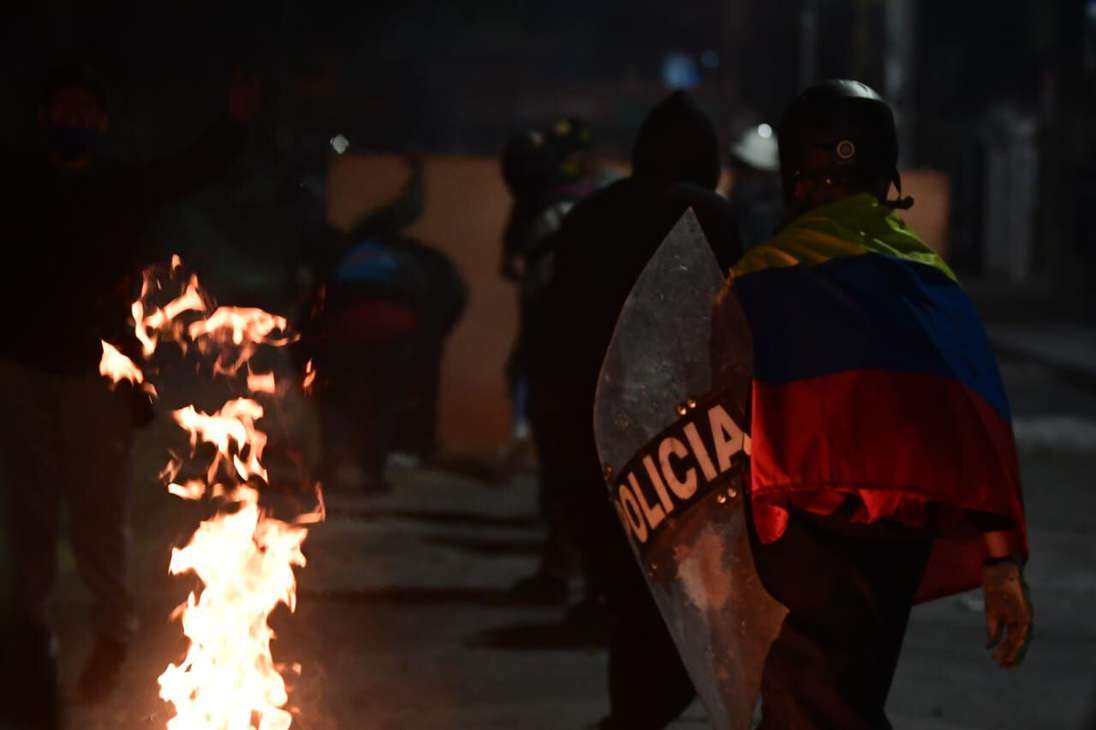 Un hombre de espaldas con la bandera de Colombia y parte de un escudo de la Policía