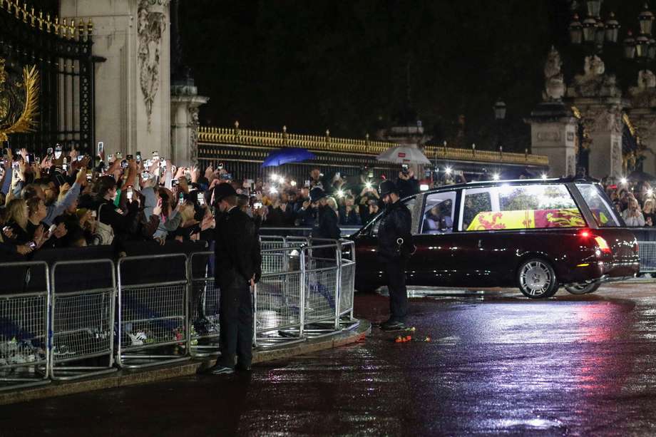 Agentes de policía inclinan la cabeza mientras el coche fúnebre que transporta el ataúd de la reina Isabel II de Gran Bretaña se dirige hacia las puertas del Palacio de Buckingham en Londres, Gran Bretaña, el 13 de septiembre de 2022.