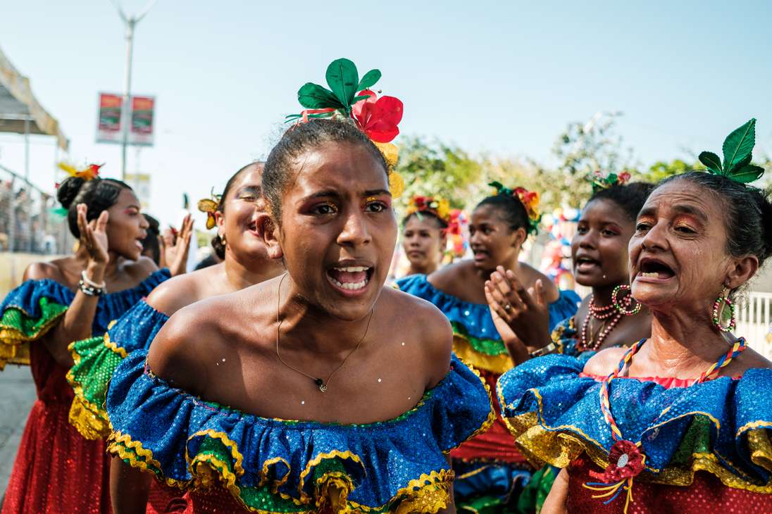 Mujeres jóvenes, adultas y mayores gritan mientras bailan por las calles de Barranquilla.