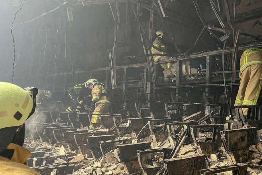Una fotografía tomada de un vídeo distribuido por el Ministerio de Emergencias de Rusia muestra cómo los rescatadores examinan los escombros en la sala quemada de la sala de conciertos Crocus City Hall tras un ataque terrorista en Krasnogorsk, en las afueras de Moscú, Rusia, el 23 de marzo de 2024.
