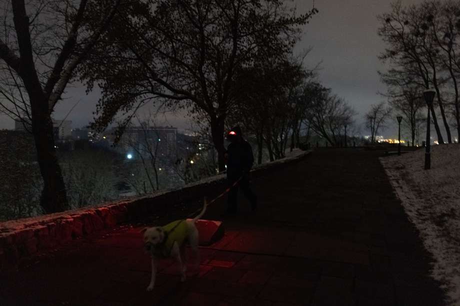 Un hombre camina con un perro en un parque durante un apagón en el centro de Kiev. La llegada del invierno traerá condiciones más duras a Ucrania, incluido el barro pesado, la nieve y el frío helado, que dificultarán las operaciones de ambos bandos en la guerra.
