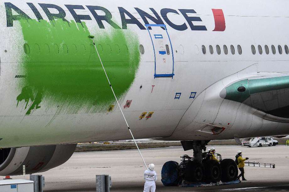 Los miembros de Greenpeace protestan pidiendo la reducción del tráfico aéreo frente a los desafíos climáticos, pintando un avión de pasajeros de Air France estacionado en la pista 'verde' en el aeropuerto internacional Roissy-Charles de Gaulle (CDG), al norte de París en marzo. 5 de febrero de 2021.