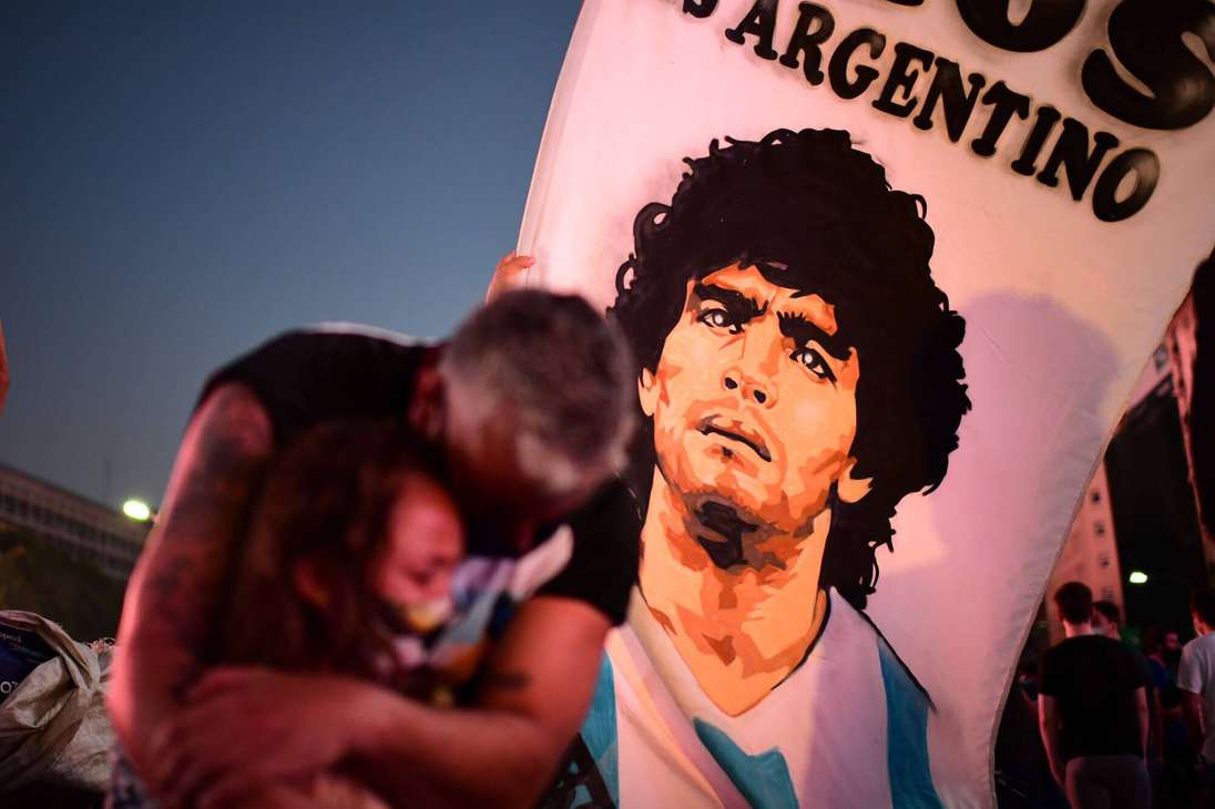 Un padre y su hija, fanáticos de la leyenda del fútbol argentino Diego Maradona, lloran mientras se reúnen junto al Obelisco para rendir homenaje el día de su muerte en Buenos Aires, el 25 de noviembre de 2020.