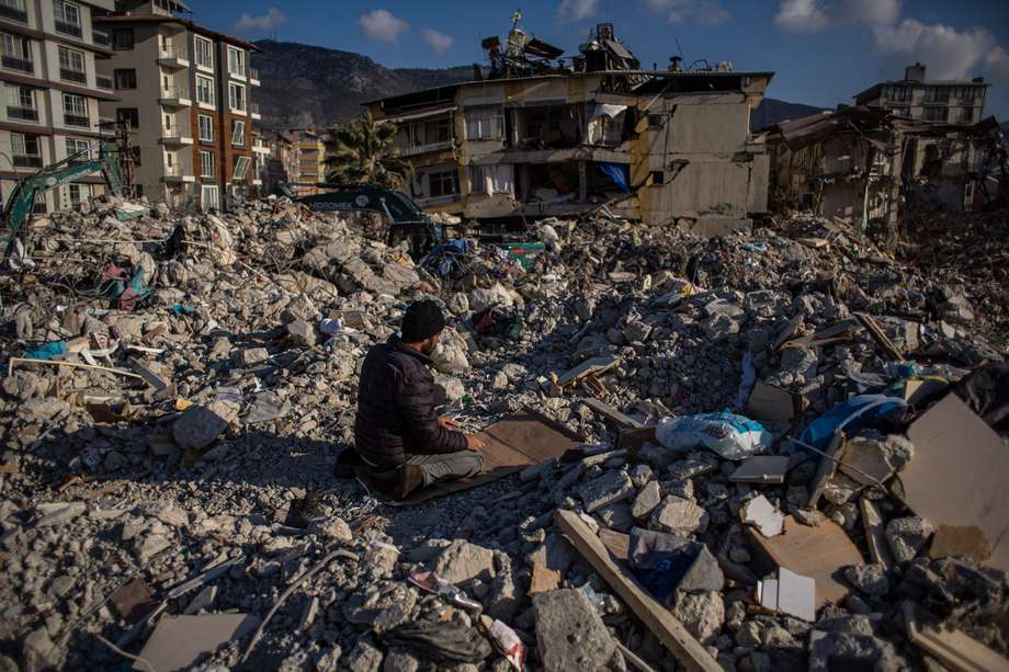 Un hombre reza sobre los escombros de los edificios derrumbados tras un fuerte terremoto, en Hatay, Turquía, el 19 de febrero de 2023.