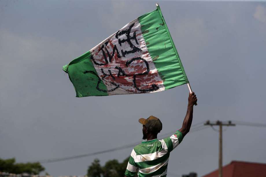 Un manifestante sostiene un bandera de Nigeria ensangrentada.