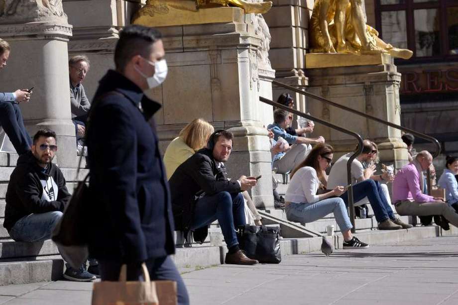 People sit on the steps of the Royal Dramatic Theater in Stockholm, Sweden, Wednesday April 22, 2020, keeping their distance amid the coronavirus COVID-19 outbreak. (Janerik Henriksson / TT via AP)