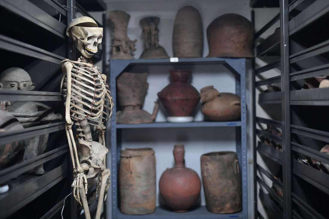 En medio de los anaqueles, donde se almacenan las piezas arqueológicas, un esqueleto completo cuelga de un gancho de metal, que lo sostiene del cráneo. Está rodeado de una colección que alberga más de 16.000 bienes arqueológicos.