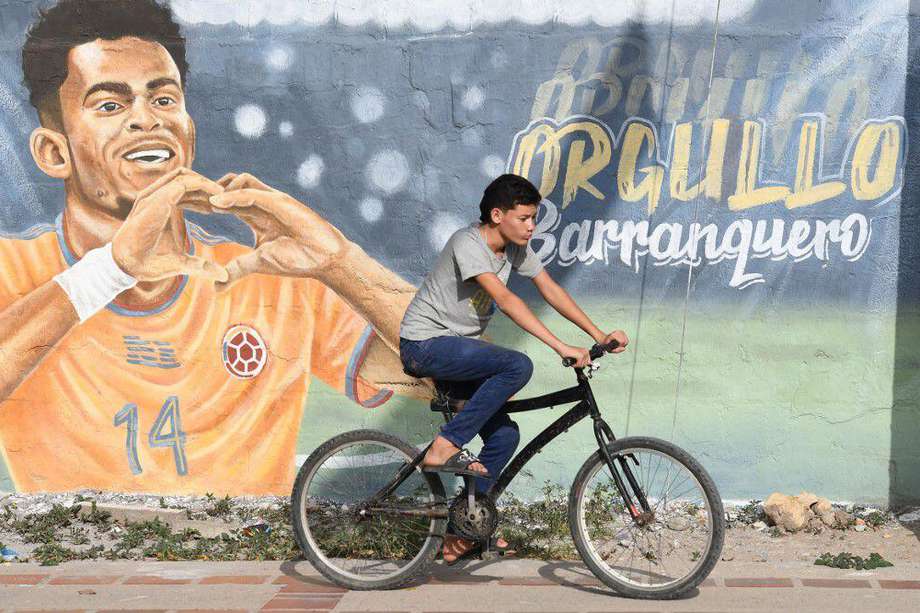 Un joven monta en bicicleta frente a un mural que representa a la estrella del fútbol del Liverpool de Inglaterra, el colombiano Luis Díaz, en Barrancas, departamento de La Guajira.