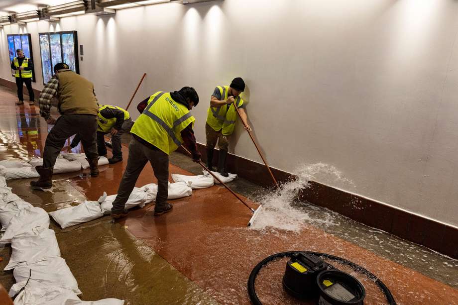 Trabajadores barren el agua que inunda un túnel subterráneo en la estación de tren Union Station, en Los Ángeles.