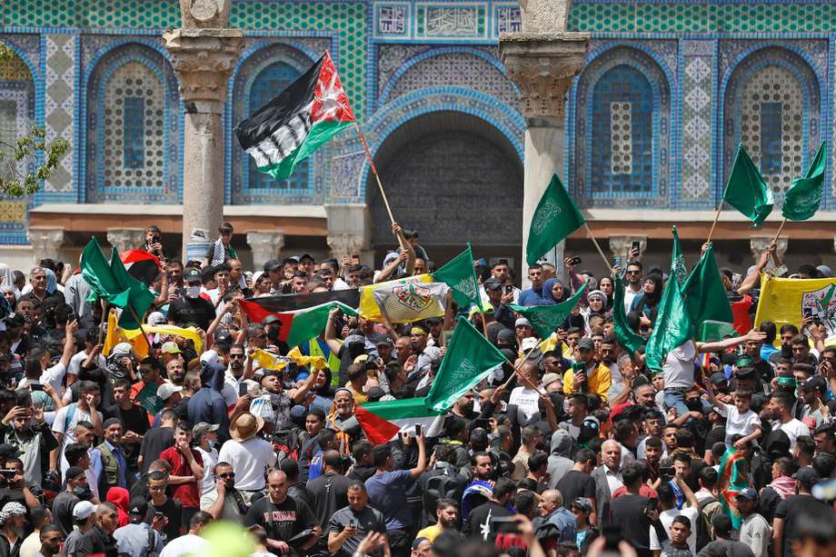 Manifestantes palestinos ondean banderas palestinas e islámicas mientras se reúnen en el complejo de la mezquita de Al-Aqsa en Jerusalén, después de las oraciones del último viernes del mes sagrado musulmán del Ramadán.
