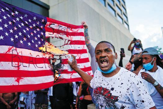 Manifestantes queman una bandera estadounidense frente a CNN en Atlanta, Georgia. 