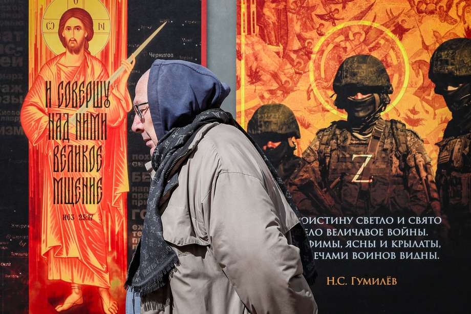Un hombre pasa junto a una instalación con fotografías de soldados rusos durante una exposición callejera titulada "¡Traemos la paz!" en Moscú, Rusia.