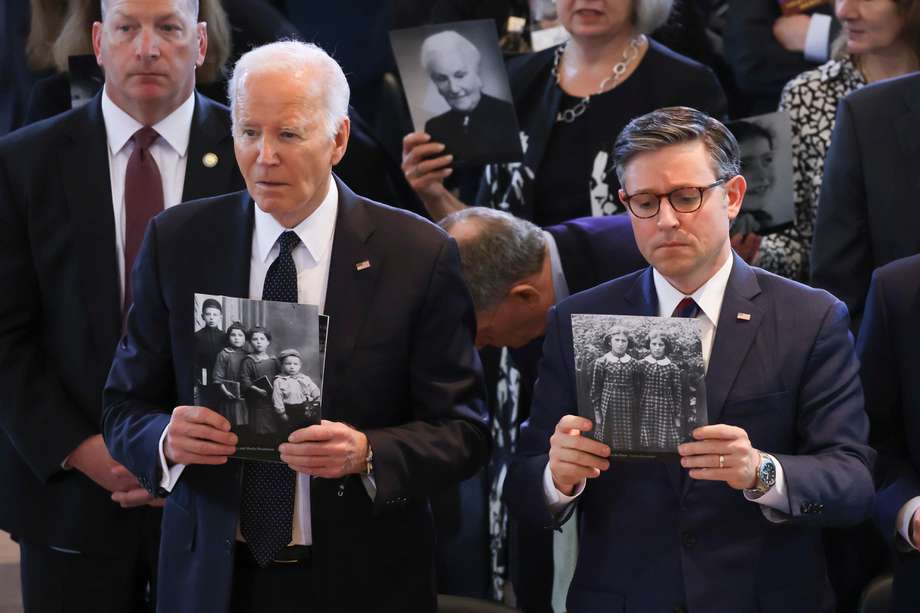 El mandatario estadounidense, Joe Biden, y el presidente de la Cámara de Representantes, Mike Johnson, sostienen fotografías de personas que murieron durante el Holocausto, durante un evento conmemorativo en el Capitolio. 