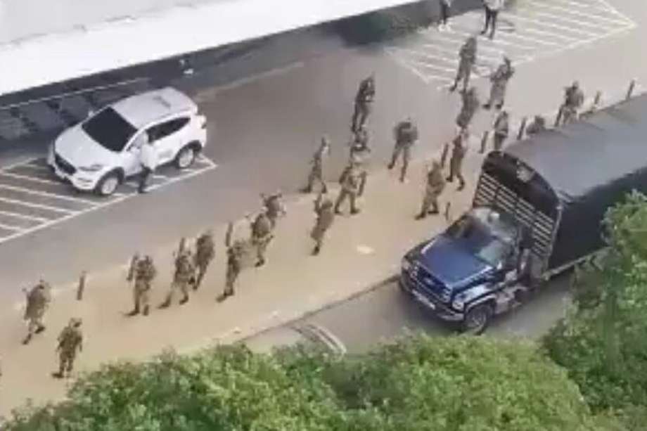 Hombres del ejército descienden de un camión parqueado frente a una de las entradas del centro comercial Cacique.