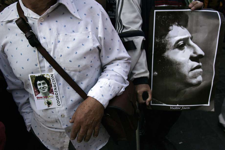 Un hombre sostiene un retrato del cantante chileno Víctor Jara, durante su funeral de tres días en Santiago el 5 de diciembre de 2009, seis meses después de que sus restos, enterrados en secreto durante 36 años tras su muerte a manos de agentes de la dictadura de Augusto Pinochet (1973-1990) )-- fueron exhumados por orden judicial en el marco de una investigación sobre su muerte.